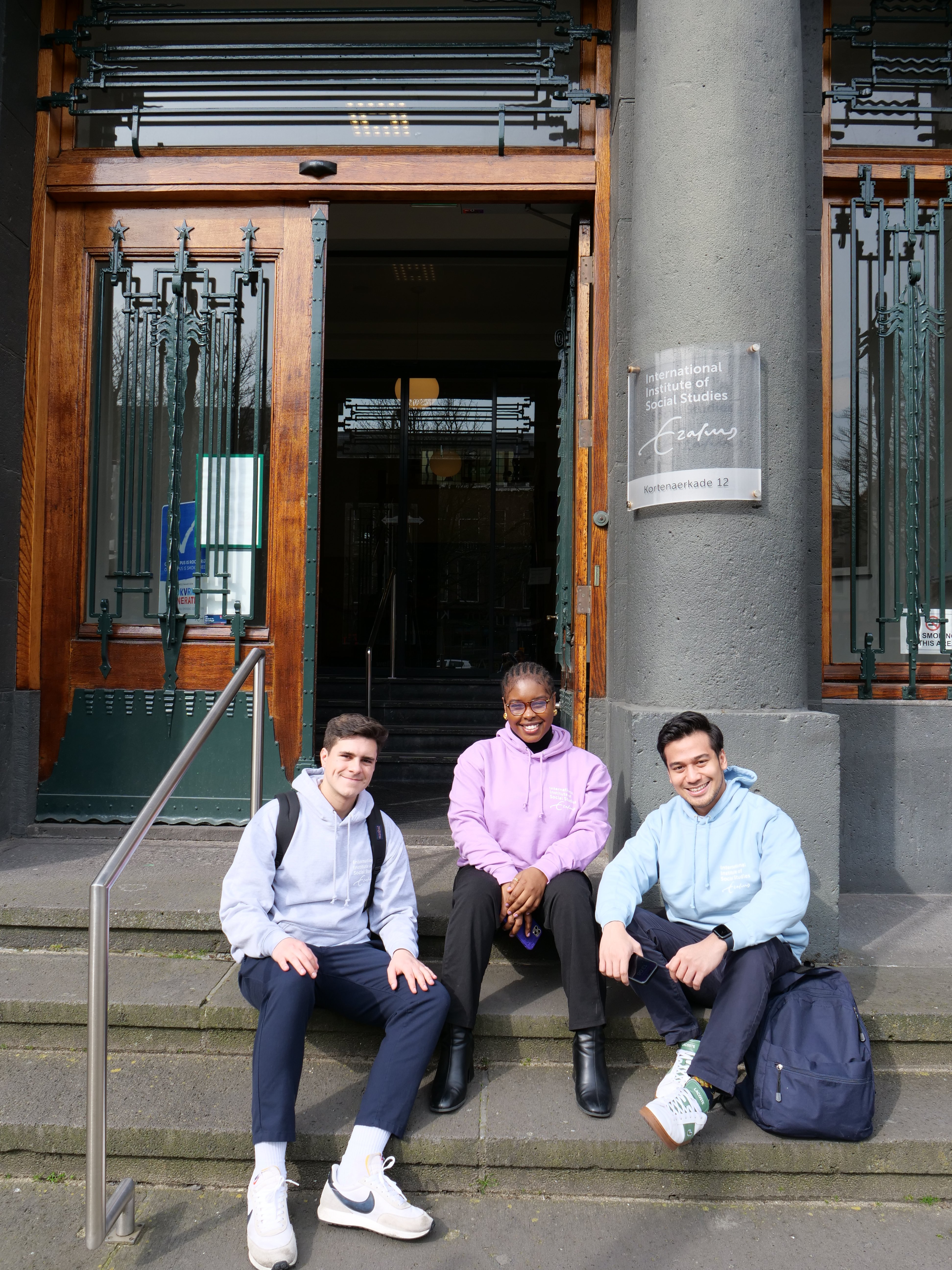 Three ISS students in sitting outside ISS