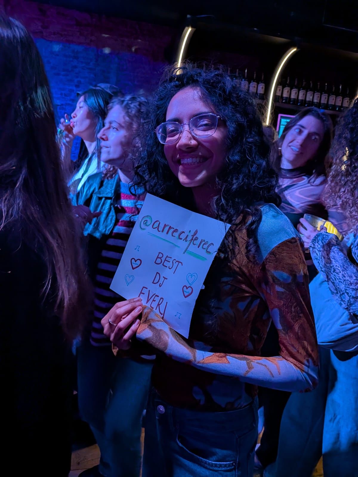 Young woman holding up a hand-made sign supporting a DJ