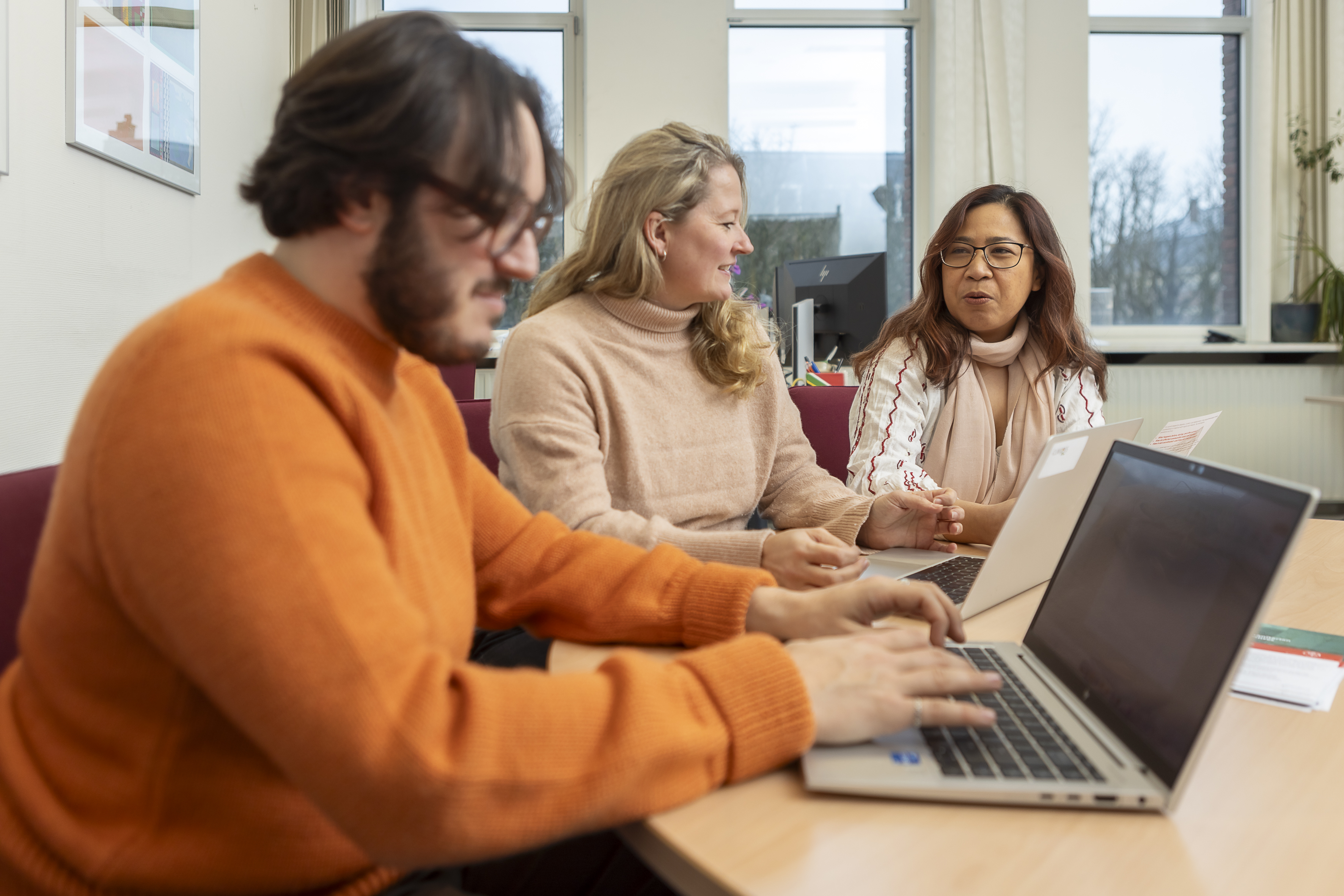 Three people sitting at desks with laptops